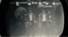 a group of men in tuxedos are standing in front of a microphone in front of a sign that says cornerstone