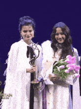 two women standing next to each other holding flowers and a trophy with the year 2020 on the bottom right