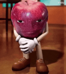 a cartoon apple with arms and legs is sitting on the floor with his hands folded .