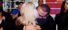 a man and a woman are hugging and kissing in front of a crowd of people .