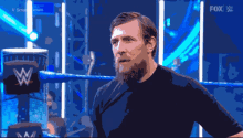 a man with a beard stands in a wrestling ring with a fox logo in the corner