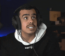 a man wearing headphones with the word oops on his sweatshirt