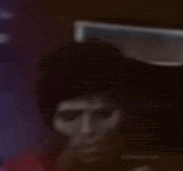 a close up of a man 's face with glowing eyes and a red shirt .