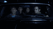 a group of people are sitting in a car and one of them is looking at the rear view mirror