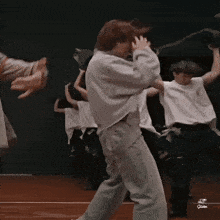 a group of people are dancing on a stage and one of them is wearing a white shirt .