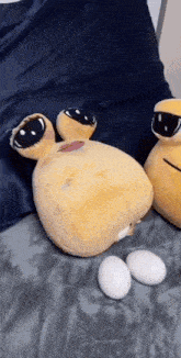 two stuffed animals are laying on a bed next to eggs