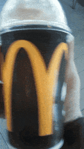 a person is holding a mcdonald 's cup that has a yellow m on it