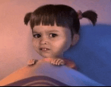 a little girl is sitting on a bed with her hands on her stomach .