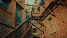 a woman stands on a fire escape in front of a building that has a sign on it that says kensington coal co