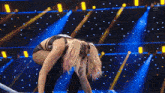 a female wrestler is kneeling down in front of a blue and yellow background