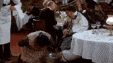 a man is sitting at a table with a woman kneeling on his lap