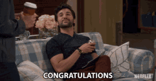 a man sitting on a couch with the words congratulations on the bottom right