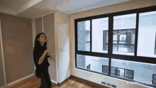 a woman is standing in a room with a window and the words made in animatica on the bottom right