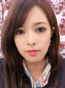 a close up of a woman 's face with cherry blossoms behind her