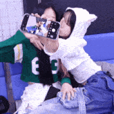 two girls are taking a selfie with a phone that says n on the screen