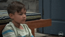 a young boy sitting on a bench with a abc logo on the bottom right
