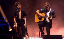 a man playing a guitar and a woman singing into a microphone