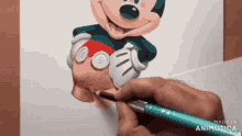 a person is drawing mickey mouse on a piece of paper with a pen