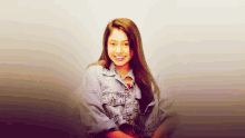 a young woman wearing a denim jacket smiles for the camera
