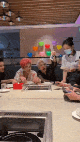 a group of people sitting at a table in a restaurant with a waitress wearing a face mask