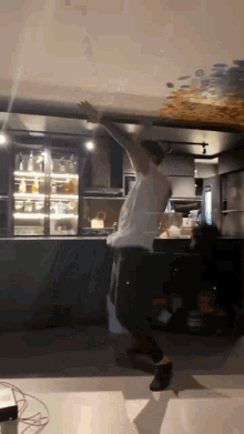 a man is dancing in a kitchen with his arms in the air