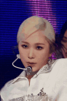 a close up of a woman wearing a microphone and a white shirt on a stage .