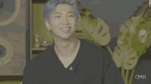 a man with blue hair is wearing a black shirt and pointing his finger at something .