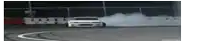 a white car is drifting on a track with smoke coming out of the tires .