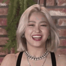 a woman with blonde hair is smiling and wearing a necklace .