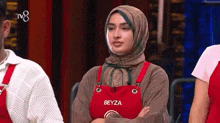 a woman in a hijab is wearing a red apron with the name beyza on it