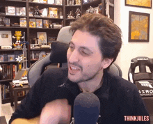 a man sitting in front of a microphone with the words think jules written on the bottom