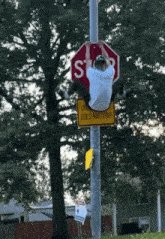 a man is hanging from a stop sign and a sign that says " does not stop "