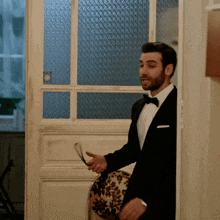 a man in a tuxedo is standing in front of a glass door