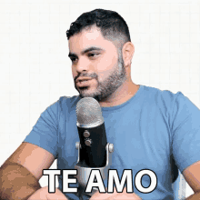 a man in a blue shirt is sitting in front of a microphone that says te amo on it