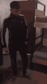 a man is standing in a room with bunk beds and a dresser .