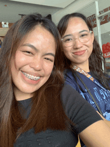 two women are posing for a picture and one has a lanyard around her neck that says ' i am a filipino '