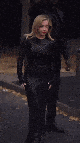a woman in a black dress is holding a man 's arm