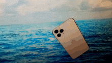 a cell phone is floating in the ocean with a blue sky in the background
