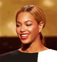 a close up of a woman smiling with red lipstick and earrings .
