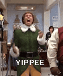 a man in a green elf costume is standing in a room with his mouth open and yipping .