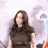 a woman with long hair is standing in front of a wall with a karina logo on it