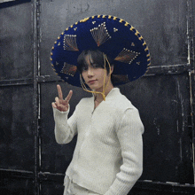 a person wearing a sombrero and a white sweater giving a peace sign