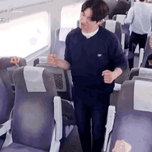 a man in a blue sweater is standing in a train car .