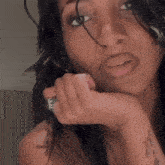 a close up of a woman 's face with a ring on her finger .