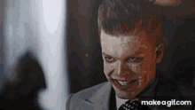 a man in a suit and tie is smiling with make a gif.com in the lower right corner