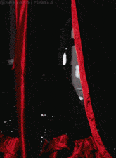 a drag queen in a red dress is holding a red fan