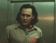 a man with long hair is standing in an elevator looking at the camera .