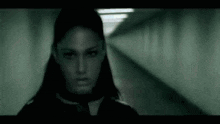 a woman with long black hair is standing in a dark tunnel looking at the camera .