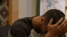 a man is holding his head in his hands while wearing sunglasses .