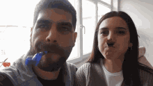 a man and a woman are making funny faces with a blue object in their mouths